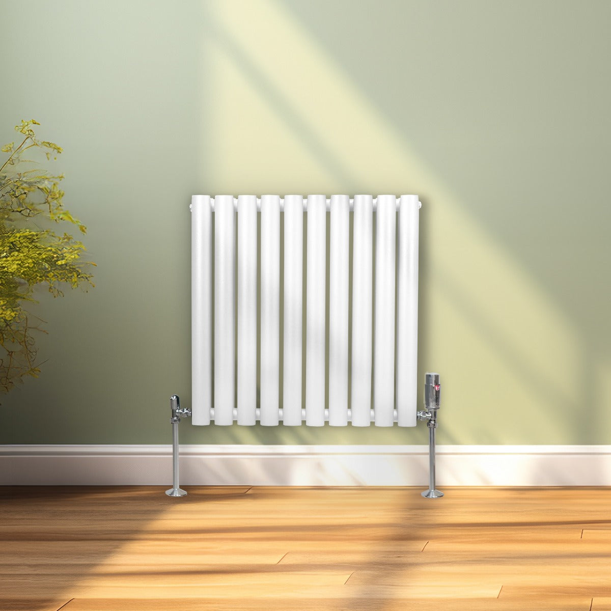 Radiador de columna ovalada blanco de 600mm x 600mm con válvulas cromadas TRV, instalado en una pared verde claro, luz suave iluminando el espacio