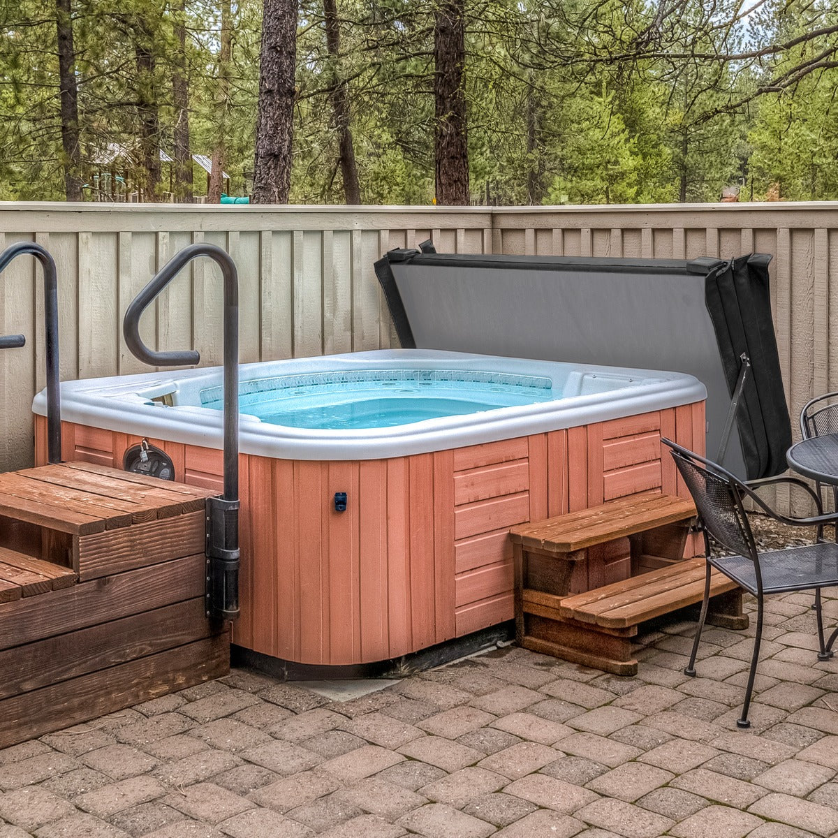 Cubierta negra para jacuzzi de 2,2m x 2,2m, con textura suave, que se adapta perfectamente al jacuzzi de madera y piedra alrededor