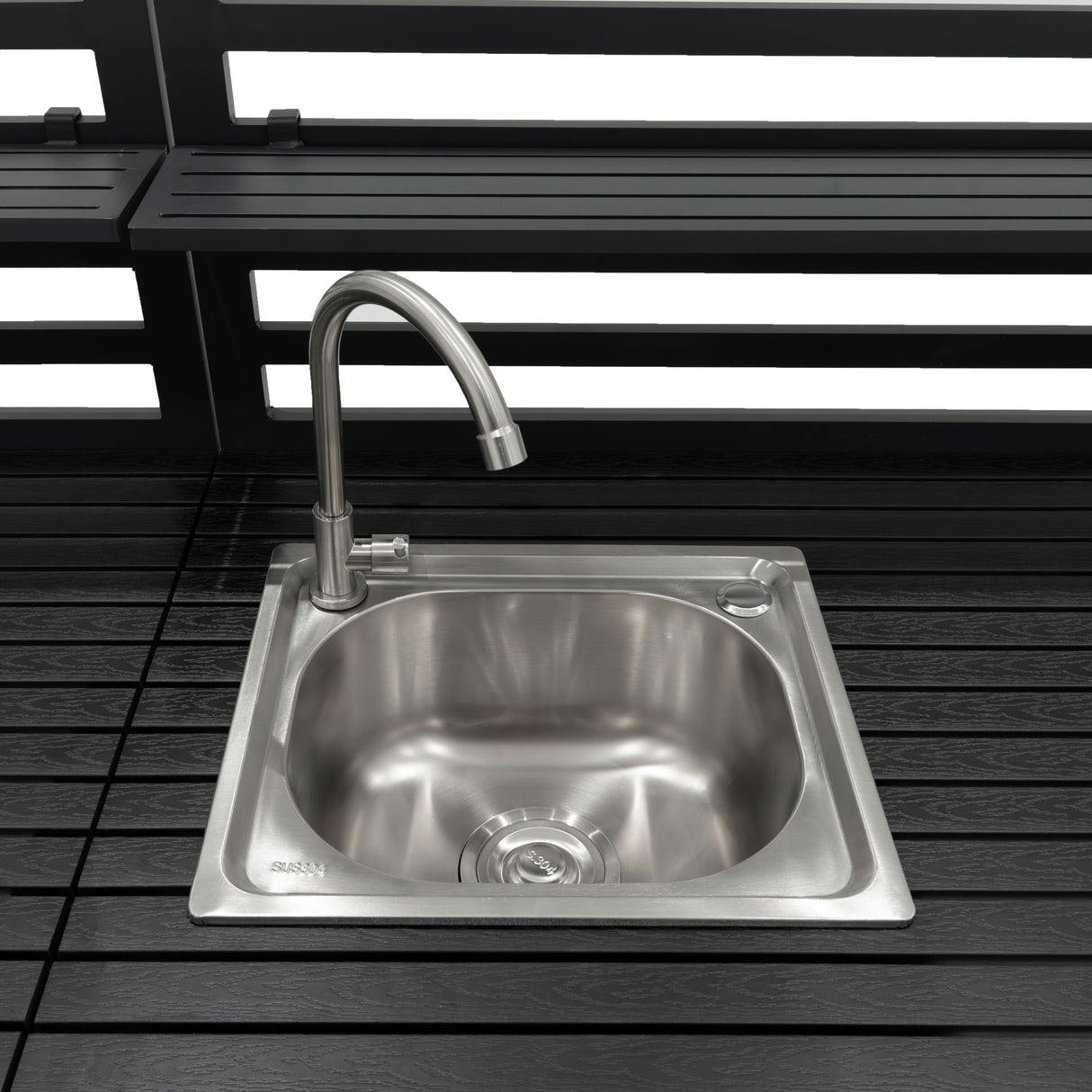 Fregadero de acero inoxidable con grifo moderno, integrado en una cocina exterior modular de aluminio, con superficie de madera oscura