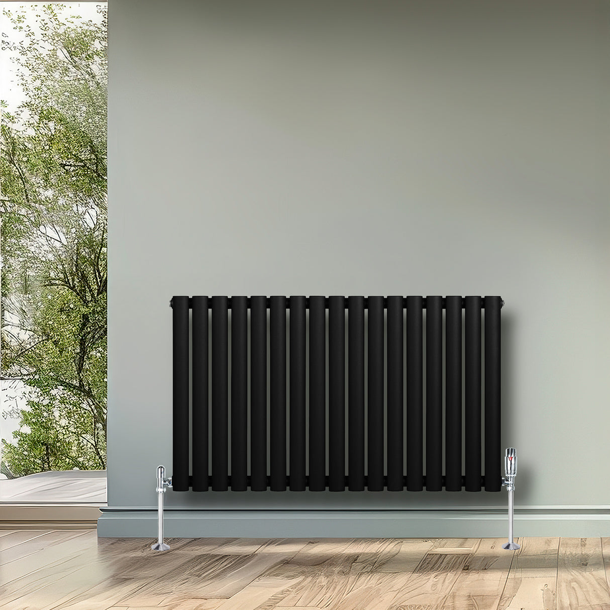 Radiador de columna ovalado negro de 600 mm x 1020 mm, con válvulas, instalado en una pared junto a una ventana con vista al jardín