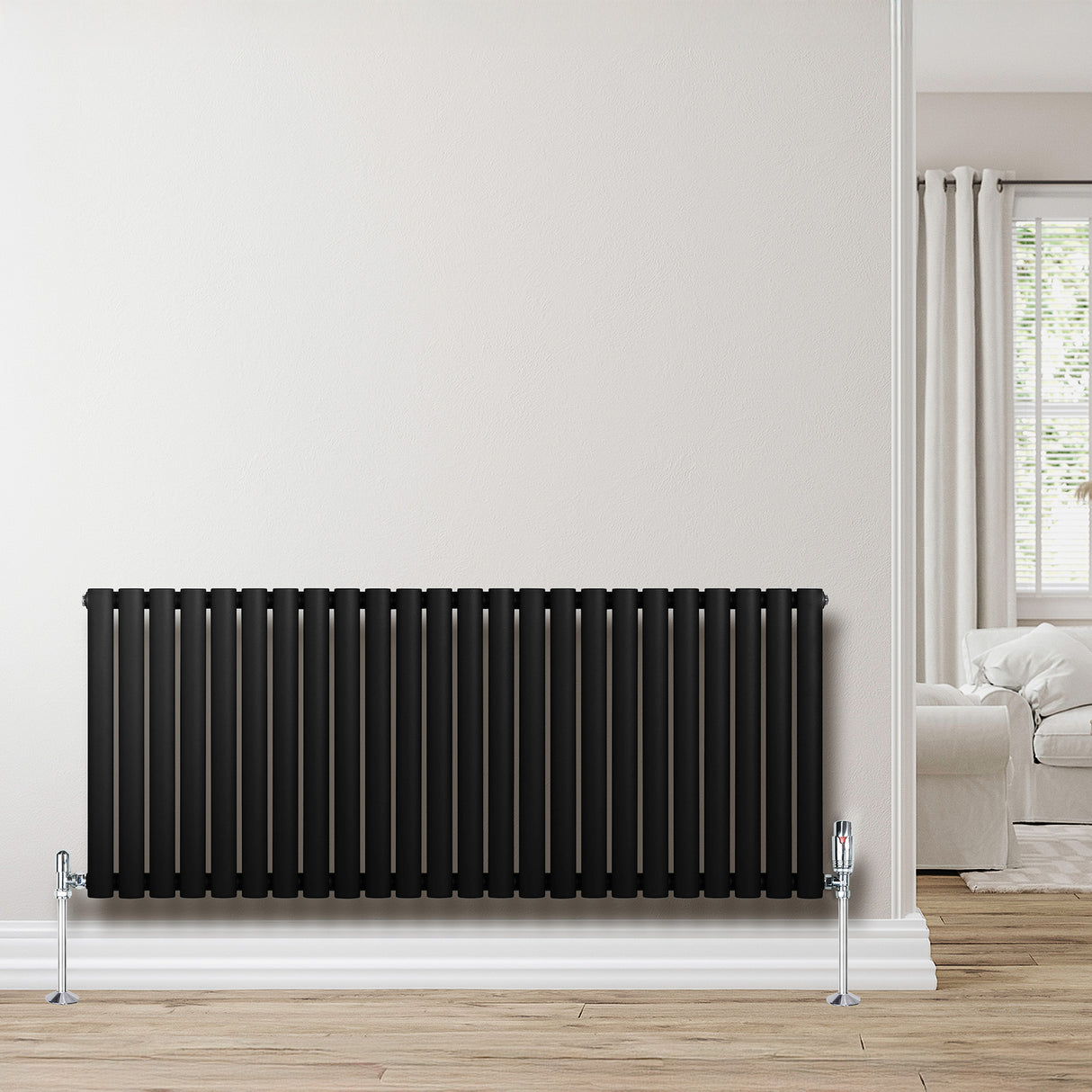Radiador de columna ovalado negro de 600 mm x 1440 mm, con válvulas, instalado en una pared clara, junto a un sofá y cortinas