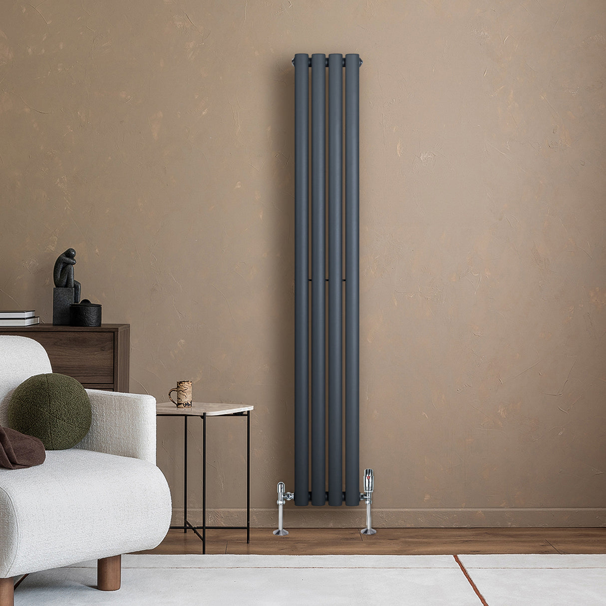 Radiador de columna ovalado gris antracita de 1600 mm x 240 mm, con válvulas, instalado en pared de color beige, junto a un sofá claro