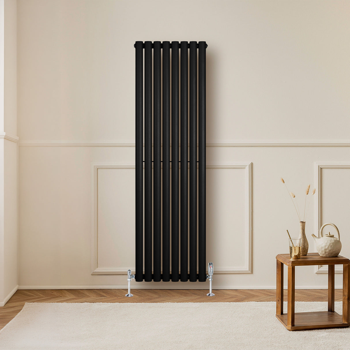 Radiador de columna ovalado negro de 1600 mm x 480 mm, con válvulas, instalado en una pared clara, complementando un ambiente moderno