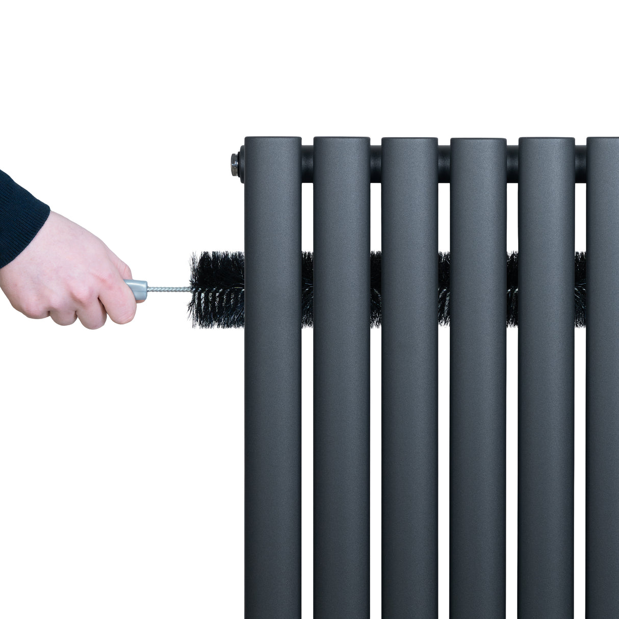 Radiador de columna ovalado en gris antracita, con válvulas, mientras se limpia con un cepillo negro, mostrando su diseño moderno y elegante
