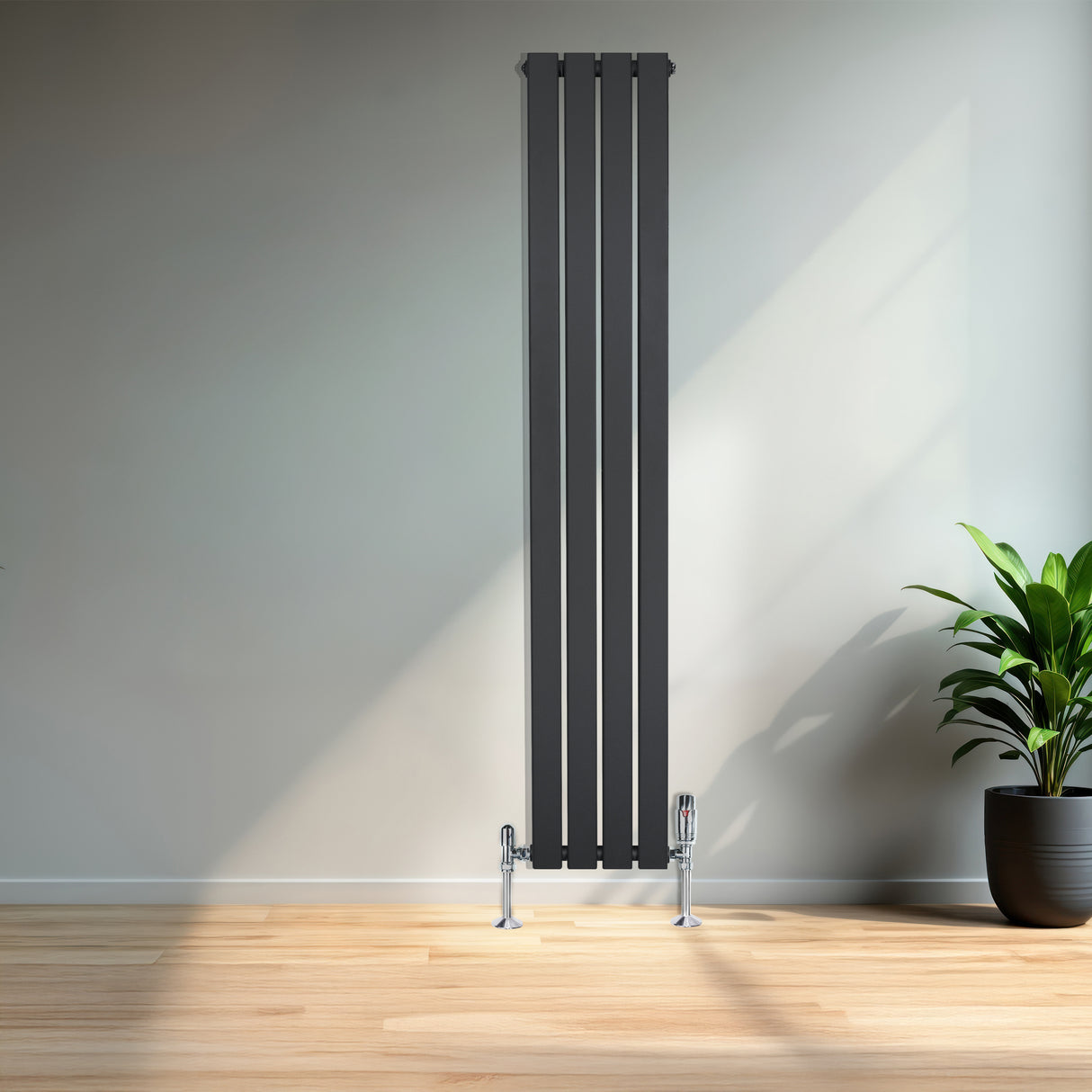 Radiador plano de columna simple gris antracita, con válvulas, de 1600 x 280 mm, instalado en una pared clara junto a una planta decorativa