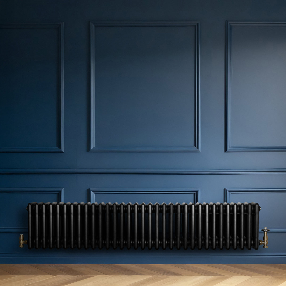 Radiador tradicional negro de 4 columnas, con válvulas, instalado en una pared azul, resaltando su diseño elegante y moderno