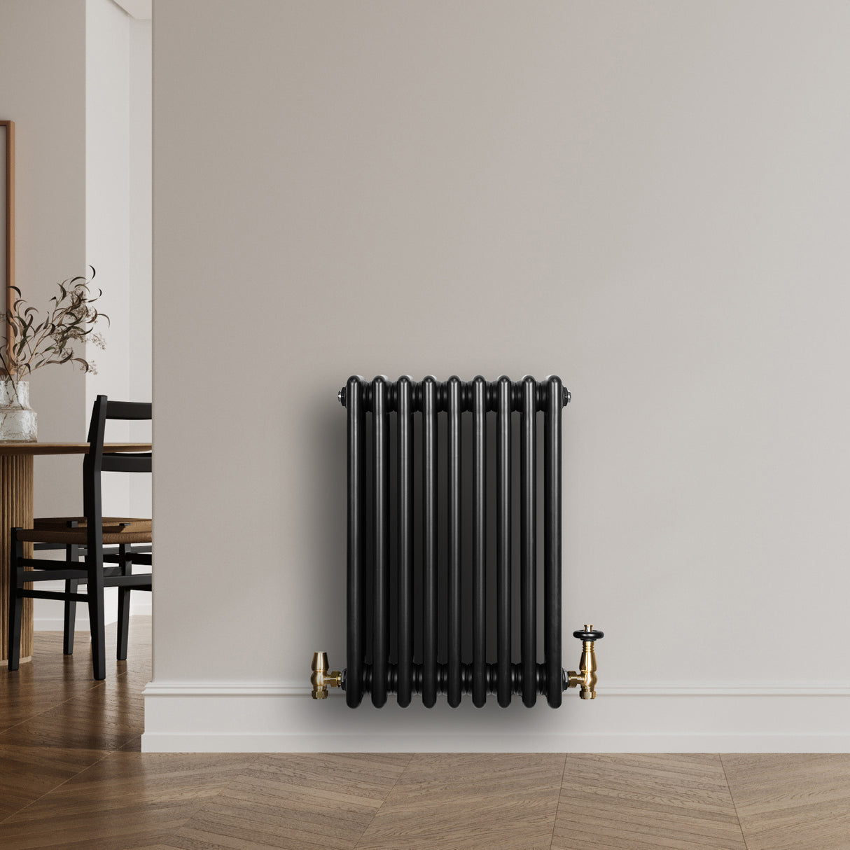 Radiador tradicional de 4 columnas en color negro, con válvulas doradas, instalado en una pared clara, ideal para decoración moderna