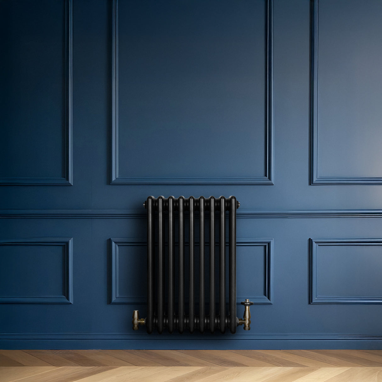 Radiador tradicional negro de 4 columnas con válvulas, instalado en una pared azul, resaltando su diseño elegante y clásico