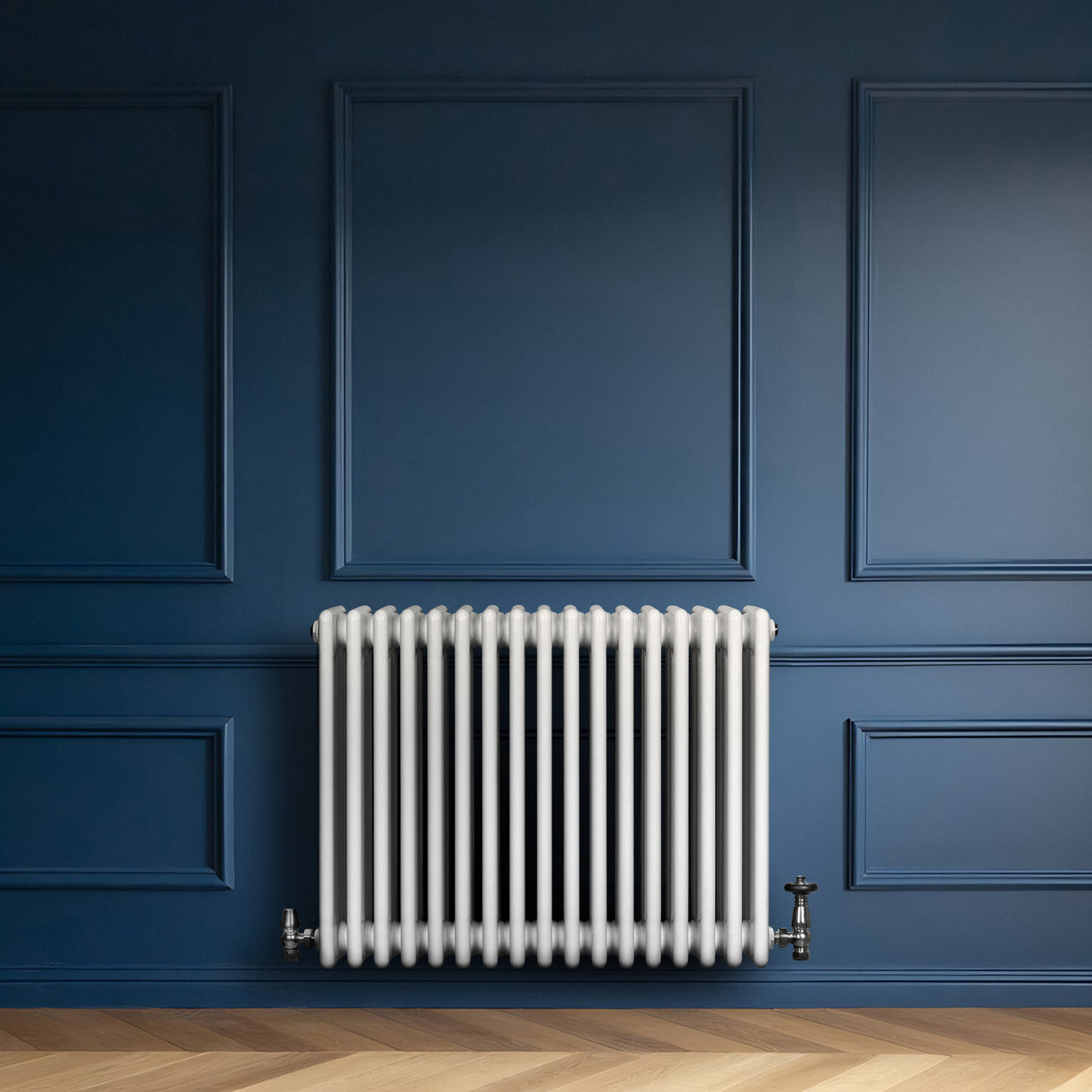Radiador tradicional de 4 columnas en color blanco, con válvulas, instalado en una pared azul, sobre un suelo de madera clara