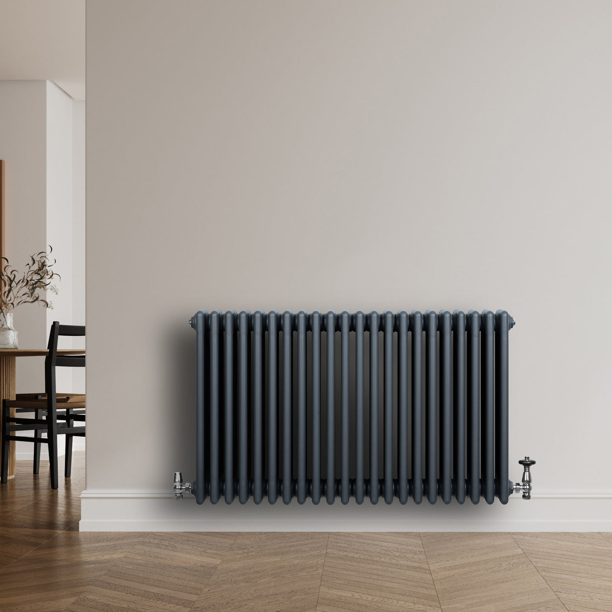 Radiador tradicional de 4 columnas en gris antracita, con válvulas, instalado en una pared clara, aportando calidez y estilo moderno