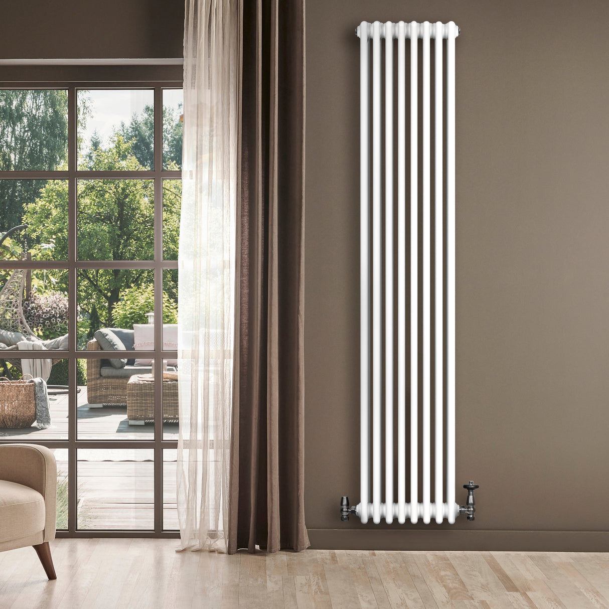 Radiador tradicional de 4 columnas en color blanco, instalado en una pared junto a una ventana con vista al exterior y cortinas marrones