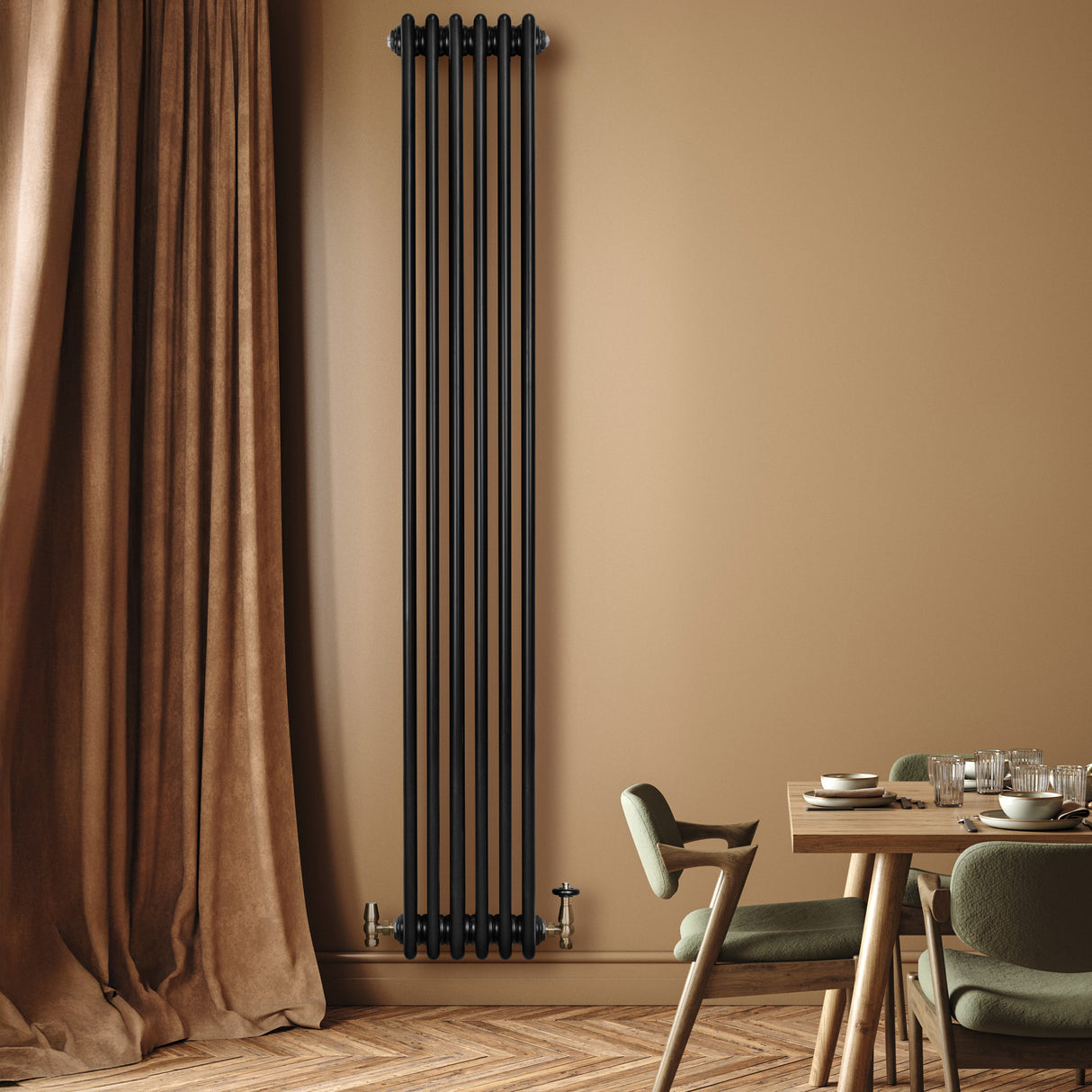 Radiador tradicional de 4 columnas en color negro, instalado en una pared beige, junto a una mesa de madera y sillas verdes