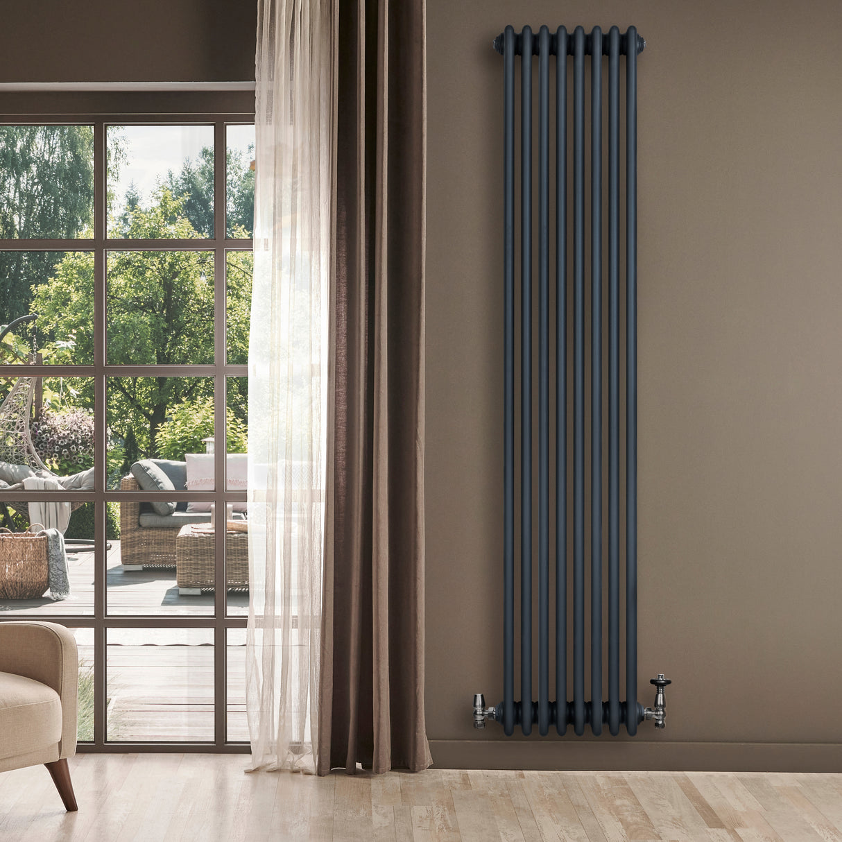 Radiador tradicional de 4 columnas en gris antracita, elegante y vertical, instalado en una pared junto a una ventana con vista al exterior