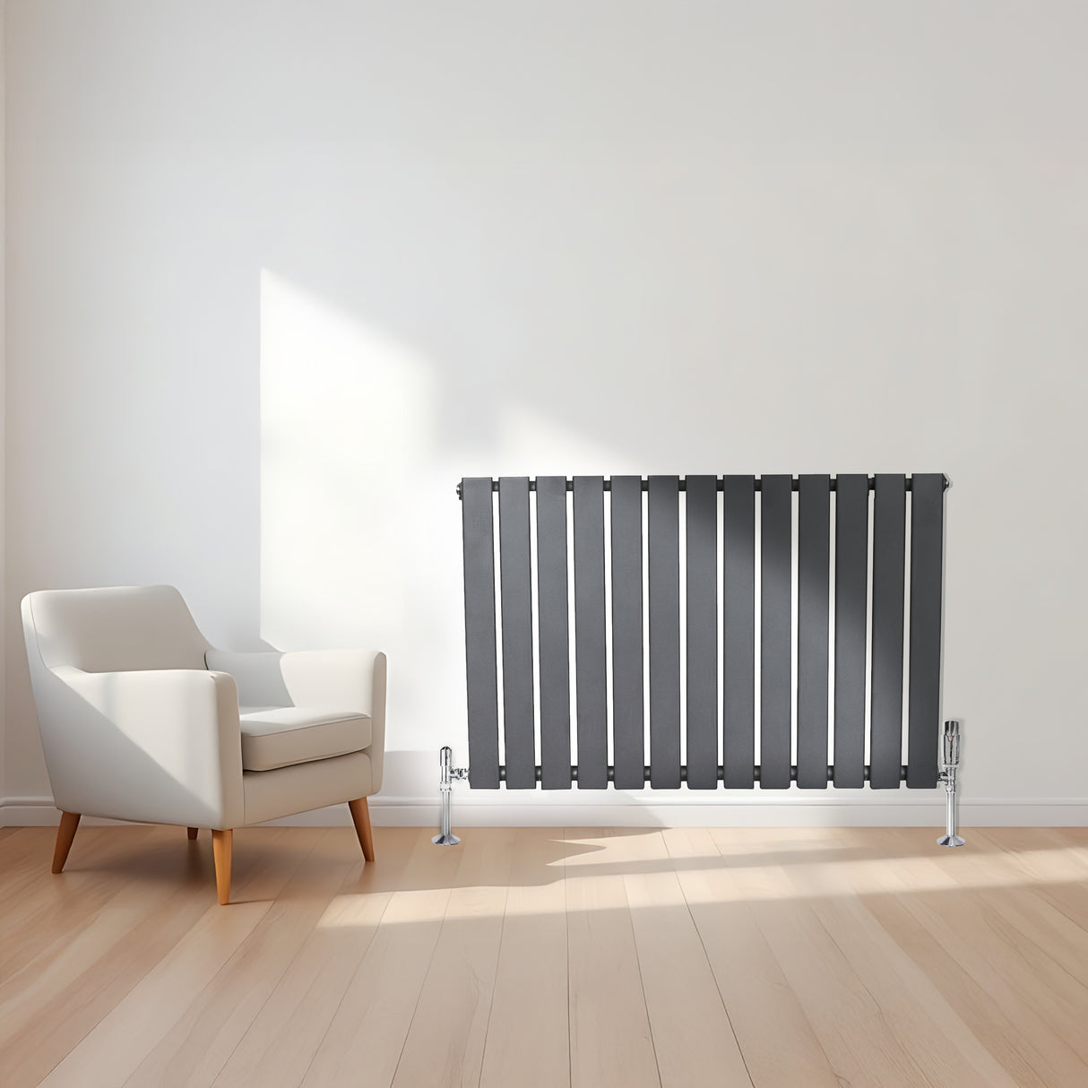 Radiador de columna única en gris antracita, con diseño vertical y acabado mate, instalado en una pared blanca junto a una silla moderna