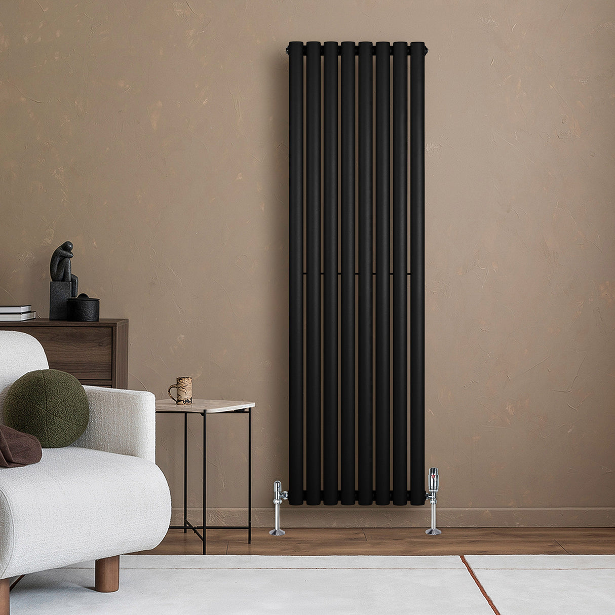 Radiador de columna ovalado negro de 1600 mm x 480 mm, con diseño moderno y acabado mate, instalado en pared beige junto a un sofá claro