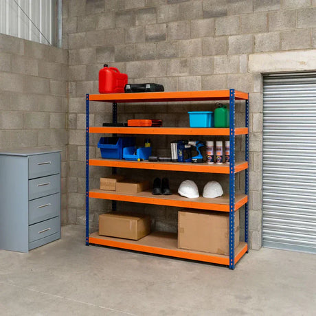 Estantería metálica naranja con estantes llenos de herramientas, cajas de cartón, botellas y cascos en un espacio de trabajo industrial