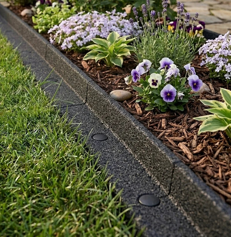 Borde de césped con flores moradas y blancas, mulch marrón y césped verde, creando un jardín ordenado y atractivo