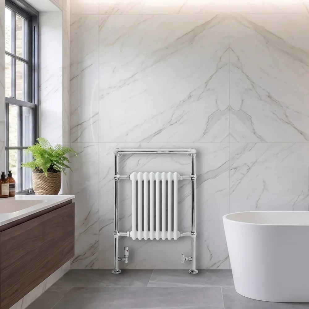 Radiador toallero tradicional de acero blanco con acabado cromado, instalado en un baño moderno con paredes de mármol y bañera blanca