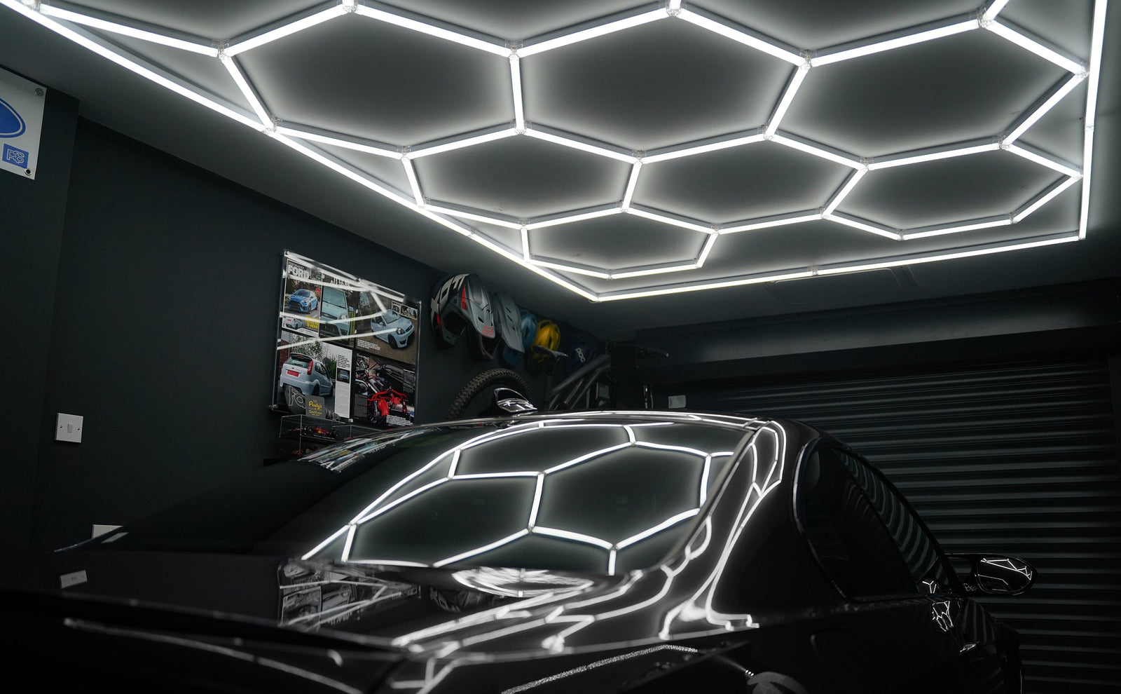 Luces LED hexagonales brillantes en un techo oscuro, reflejándose en la superficie pulida de un automóvil negro en un garaje moderno