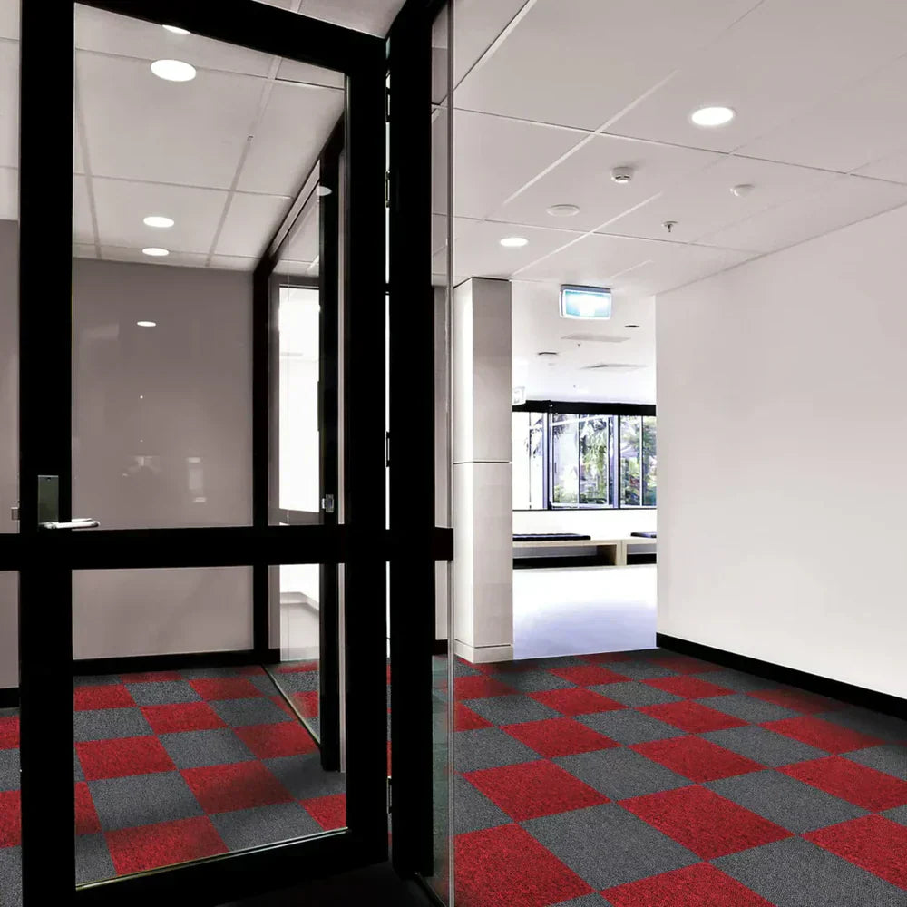 Suelo de losetas de moqueta en tonos rojo y gris, con un diseño de cuadros, en un pasillo moderno y bien iluminado