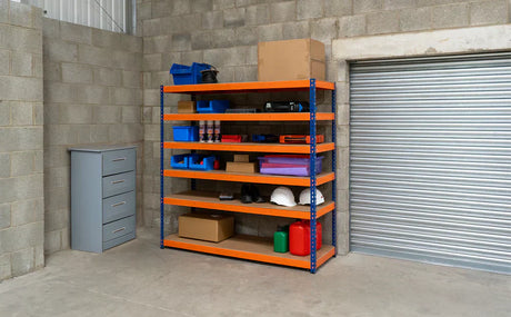 Estantería de metal naranja con estantes de madera, organizada con cajas, herramientas y artículos de almacenamiento en un garaje gris