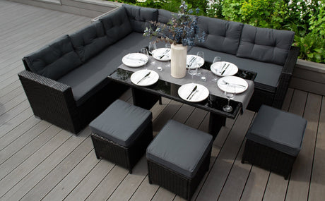 Conjunto de muebles de exterior en tonos gris oscuro, incluye sofá en forma de L y mesa negra con sillas, ideal para verano