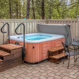 Cubierta gris para jacuzzi de 2,1m x 2,1m, con textura suave, que protege el jacuzzi en un entorno natural y acogedor