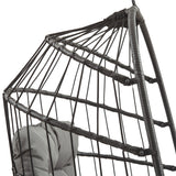 Silla colgante tipo huevo de ratán negra con estructura entrelazada y cojín gris suave, ideal para relajarse en interiores o exteriores