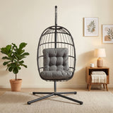Silla colgante tipo huevo de ratán negra con cojín gris, estructura metálica y base estable, ideal para interiores modernos