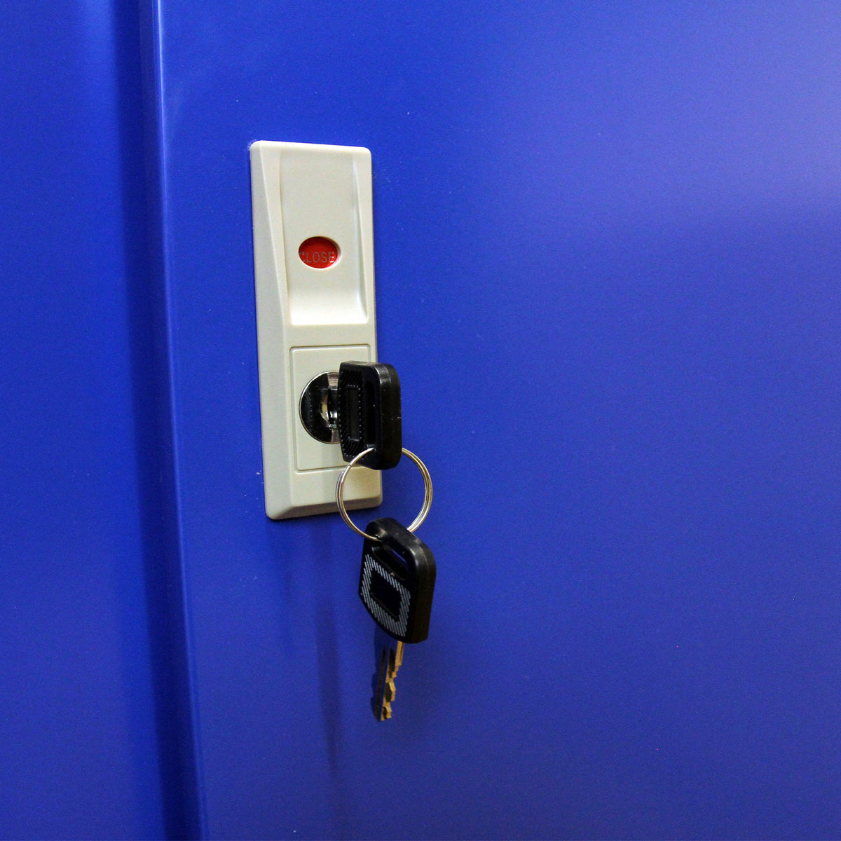 Llave colgando de un llavero en un mueble expositor azul brillante para cigarrillos y vapeadores, con botón de cierre visible