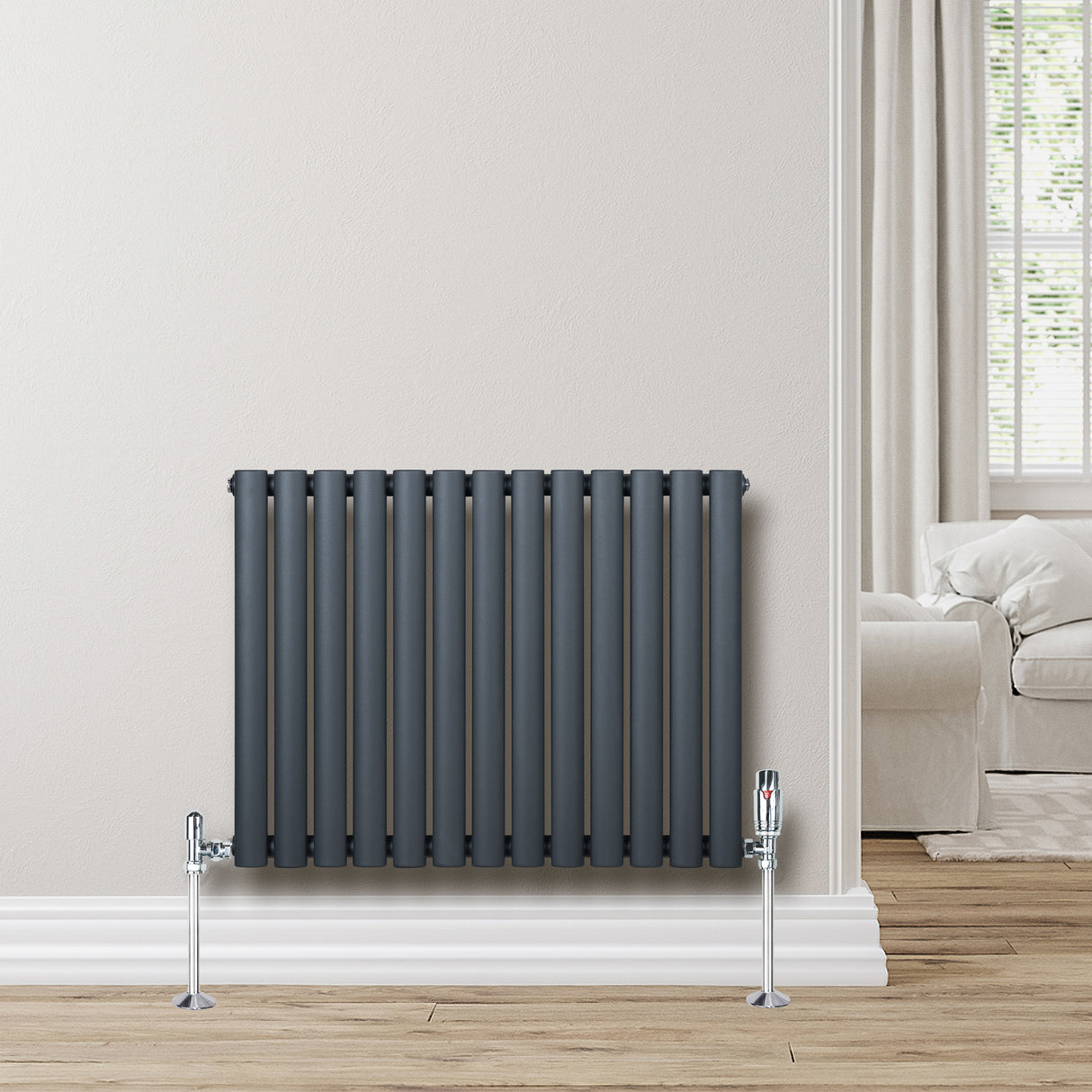 Radiador de columna ovalado en gris antracita, con válvulas, instalado en pared clara, complementando un ambiente moderno y acogedor