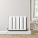 Radiador de columna ovalado blanco de 600 mm x 780 mm con válvulas, instalado en una pared clara, complementando un ambiente moderno y acogedor