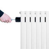 Radiador de columna ovalado blanco de 1600 mm x 480 mm, limpiado con un cepillo negro, mostrando su diseño elegante y moderno