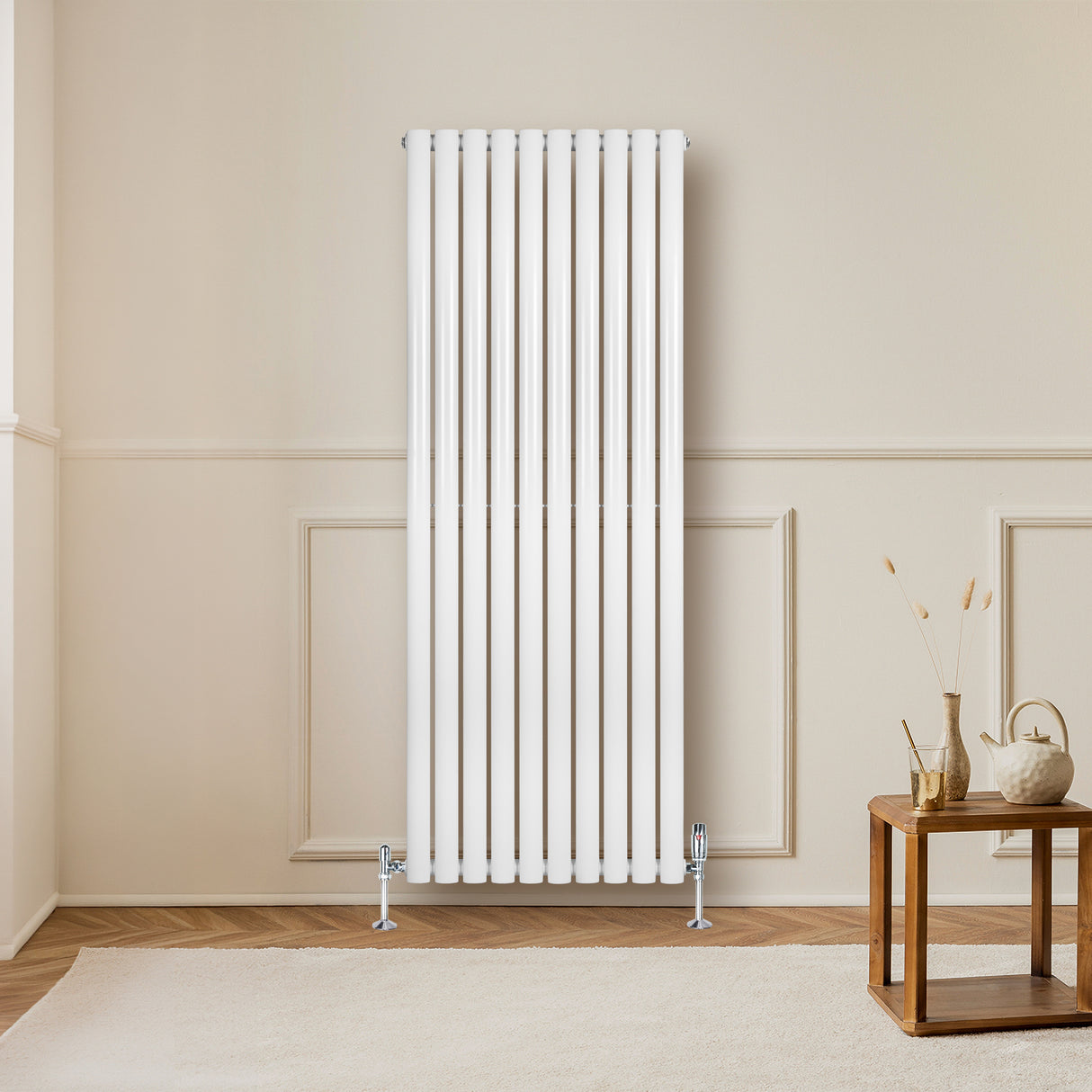 Radiador de columna ovalado blanco de 1600 mm x 600 mm, con válvulas, instalado en una pared clara, junto a una mesa de madera