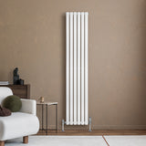 Radiador de columna ovalado blanco de 1800 mm x 360 mm, con válvulas, instalado en pared de color marrón claro, junto a un sofá moderno
