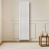 Radiador de columna ovalado blanco de 1800 mm x 480 mm con válvulas, instalado en una pared clara, complementando un ambiente moderno