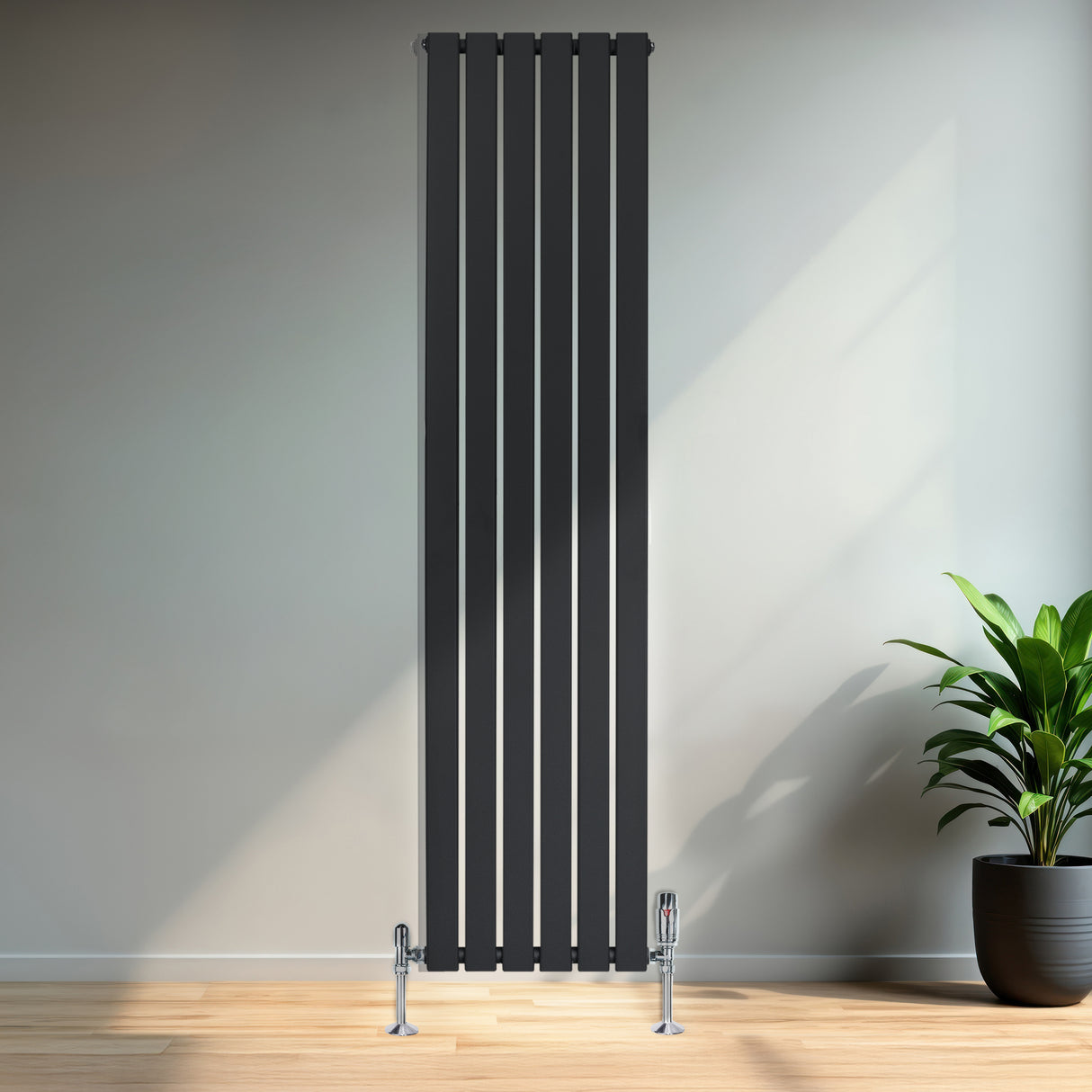 Radiador plano de columna simple en gris antracita, con diseño vertical y válvulas, colocado en una pared clara junto a una planta decorativa