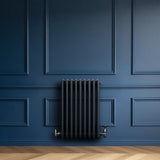Radiador tradicional de 4 columnas en gris antracita, con válvulas, montado en pared azul, destacando su diseño elegante y moderno