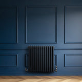 Radiador tradicional de 4 columnas en gris antracita, montado en pared azul, con válvulas metálicas y diseño elegante y clásico