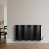 Radiador tradicional negro de 4 columnas, 600 x 1010 mm, con válvulas doradas, instalado en una pared clara y moderna