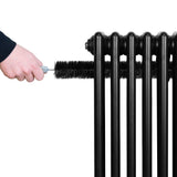 Radiador tradicional negro de 4 columnas, con válvulas, siendo limpiado con un cepillo, destacando su diseño clásico y elegante