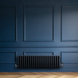 Radiador tradicional de 4 columnas en gris antracita, instalado en una pared azul, con un acabado liso y elegante, ideal para decoración moderna