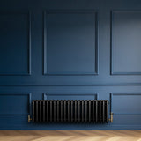 Radiador tradicional de 4 columnas en color negro, instalado en una pared azul, con acabados elegantes y diseño clásico