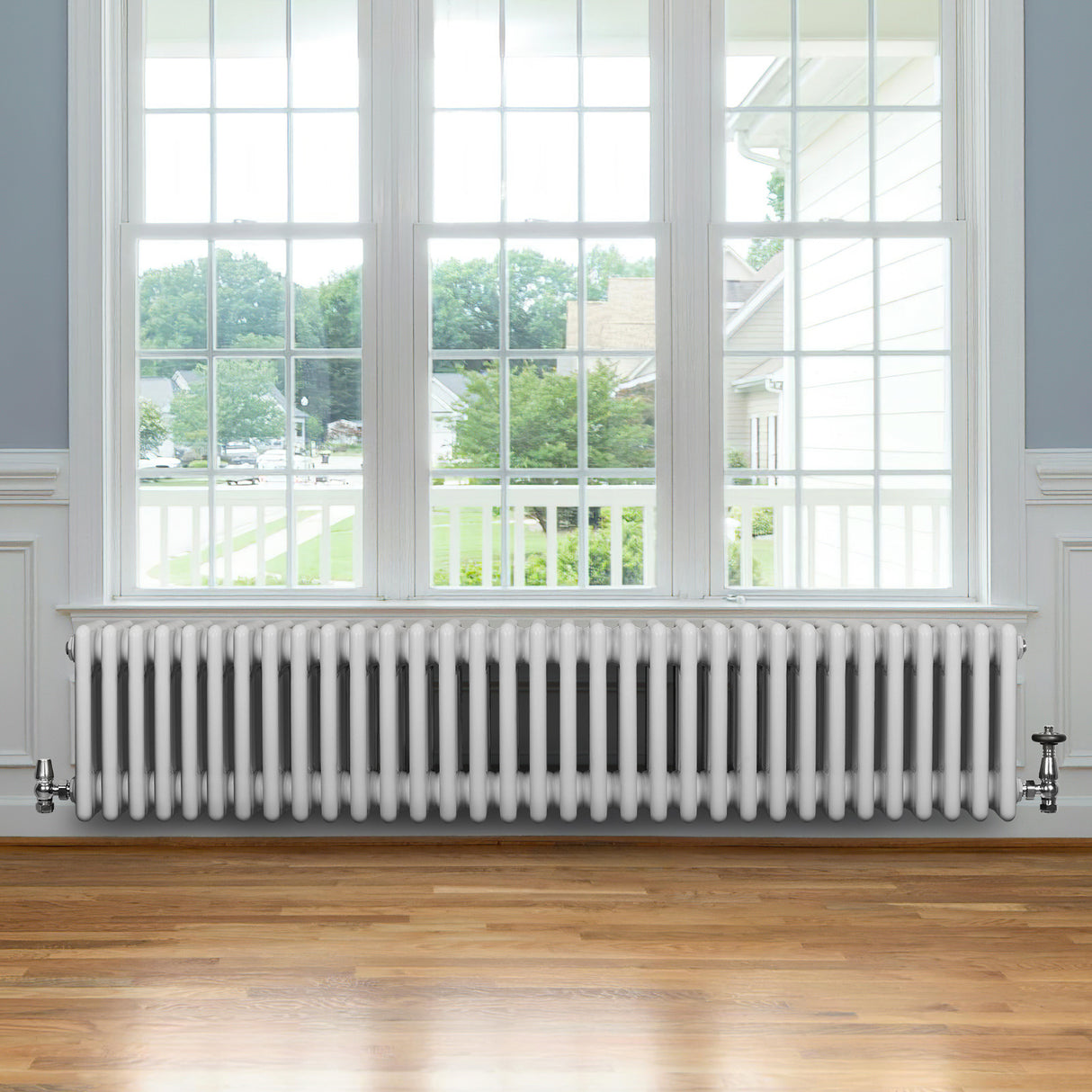 Radiador tradicional de 4 columnas en color blanco, con un diseño elegante y acabado liso, instalado bajo una ventana amplia