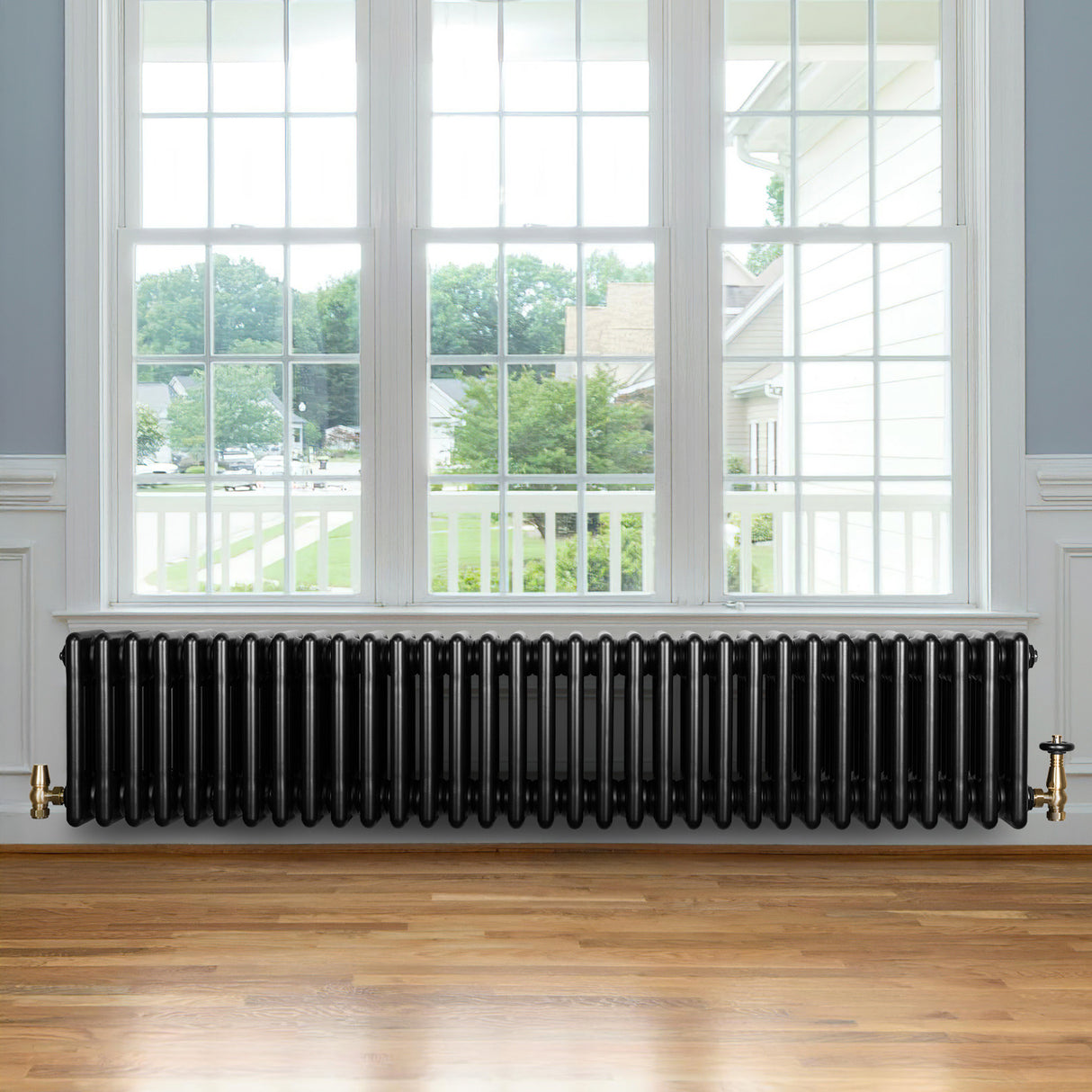 Radiador tradicional de 4 columnas en color negro, con acabado brillante y diseño elegante, instalado junto a una ventana amplia