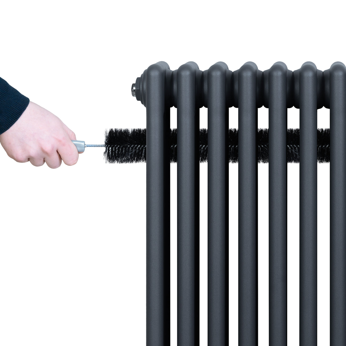 Radiador tradicional de 4 columnas en gris antracita, con una mano limpiando su superficie con un cepillo negro, textura metálica y diseño clásico