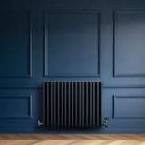 Radiador tradicional de 4 columnas en gris antracita, con un diseño elegante y acabado liso, instalado en pared azul oscuro