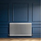 Radiador tradicional de 4 columnas, color blanco, instalado en una pared azul, con un acabado liso y elegante, ideal para calefacción