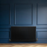 Radiador tradicional de 4 columnas en color negro, con un diseño elegante y acabado liso, instalado en una pared azul profunda