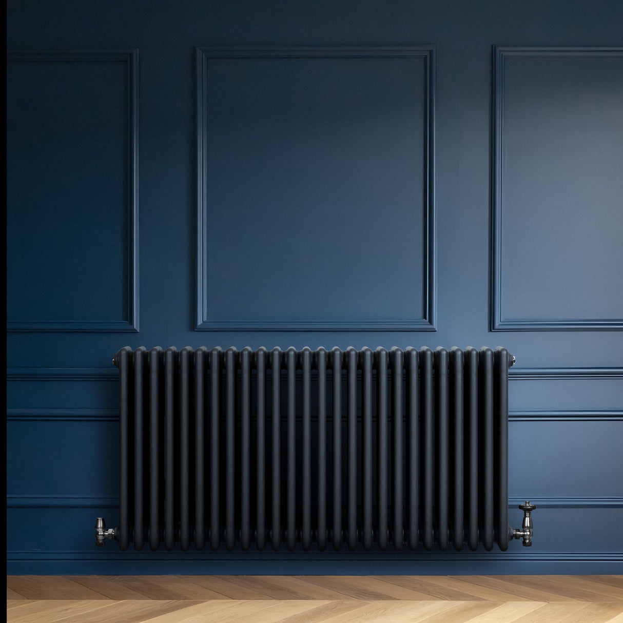 Radiador tradicional de 4 columnas en gris antracita, con un diseño elegante y acabado mate, instalado en una pared azul oscura